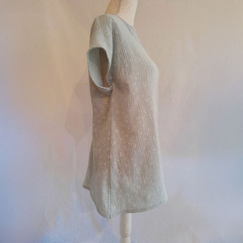 Vista trasera de blusa adaptada de algodón verde agua, pensada para vestir con comodidad y elegancia compatible con silla de ruedas.