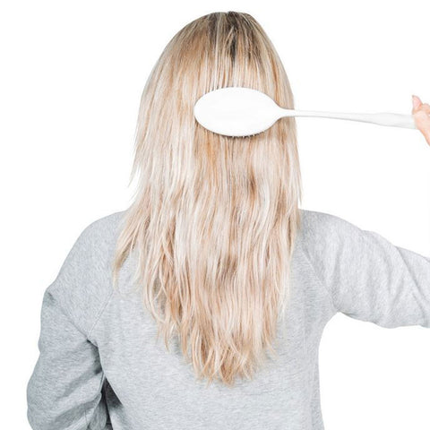 Uso del peine de mango largo para alcanzar la parte posterior de la cabeza sin levantar el brazo.