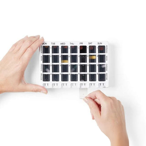 Organizador semanal de medicamentos abierto, con separación por mañana, tarde, noche y antes de dormir.