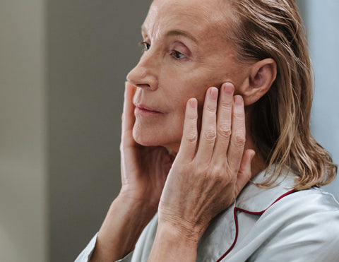 Mujer de piel madura aplicando cuidado facial para alisar líneas de expresión y prevenir el envejecimiento ocular.